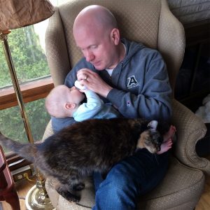 a cat and an infant share a lap